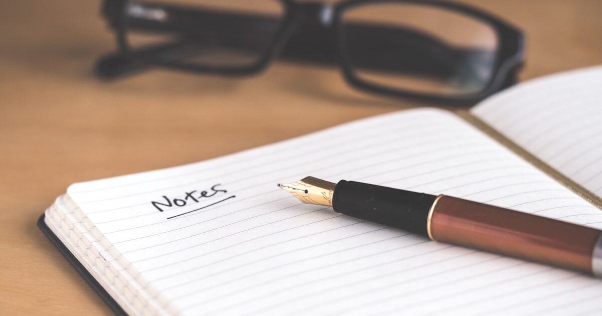 A notebook open to a medication side effect journal entry alongside prescription bottles and a pen