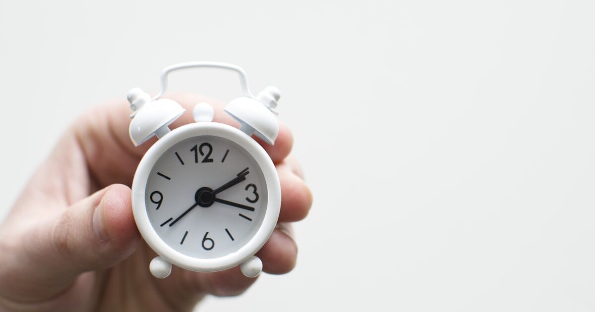 An open pill bottle next to an alarm clock on a nightstand, symbolizing missed medication doses